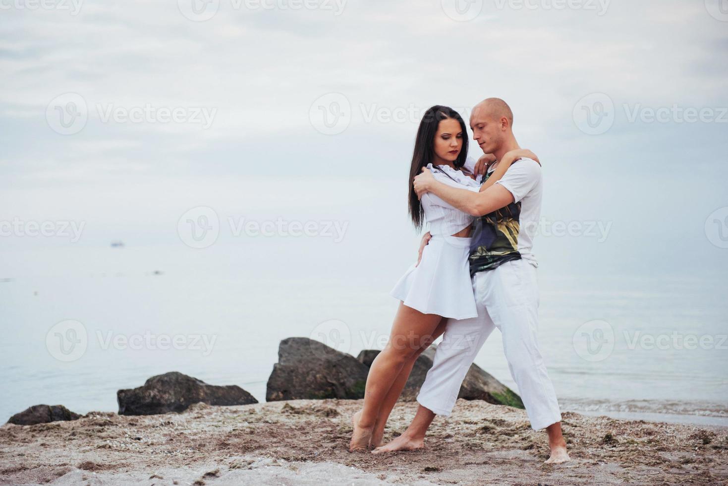 schönes entzündliches Paar, das am Strand tanzt foto