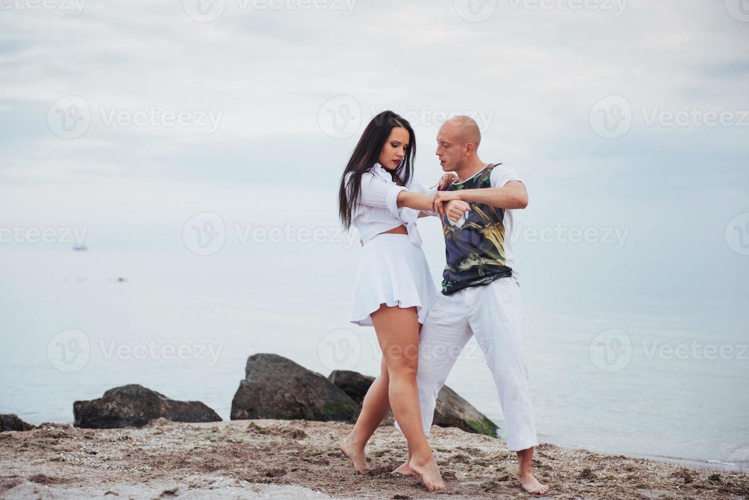 schönes entzündliches Paar, das am Strand tanzt foto