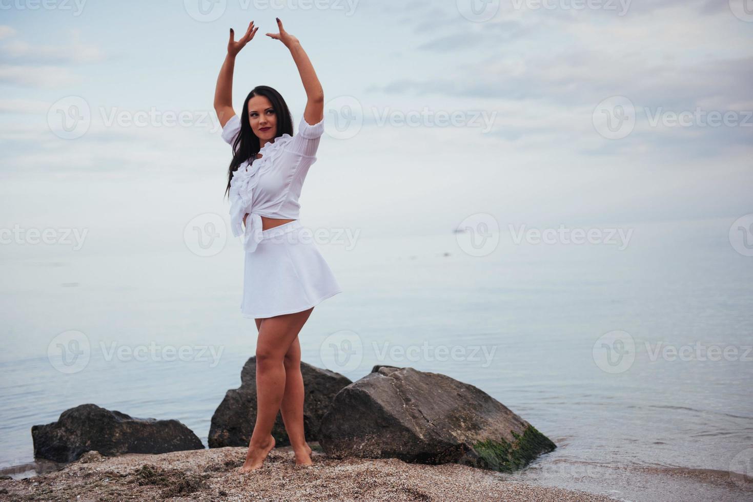 Frau in einem weißen Hemd und Rock, die barfuß tanzt foto