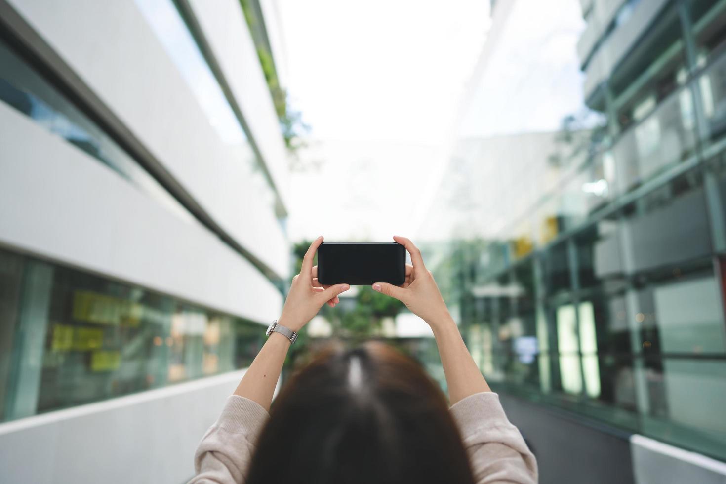 Schulteransicht einer Frau, die einen leeren Bildschirm des Mobiltelefons hält foto