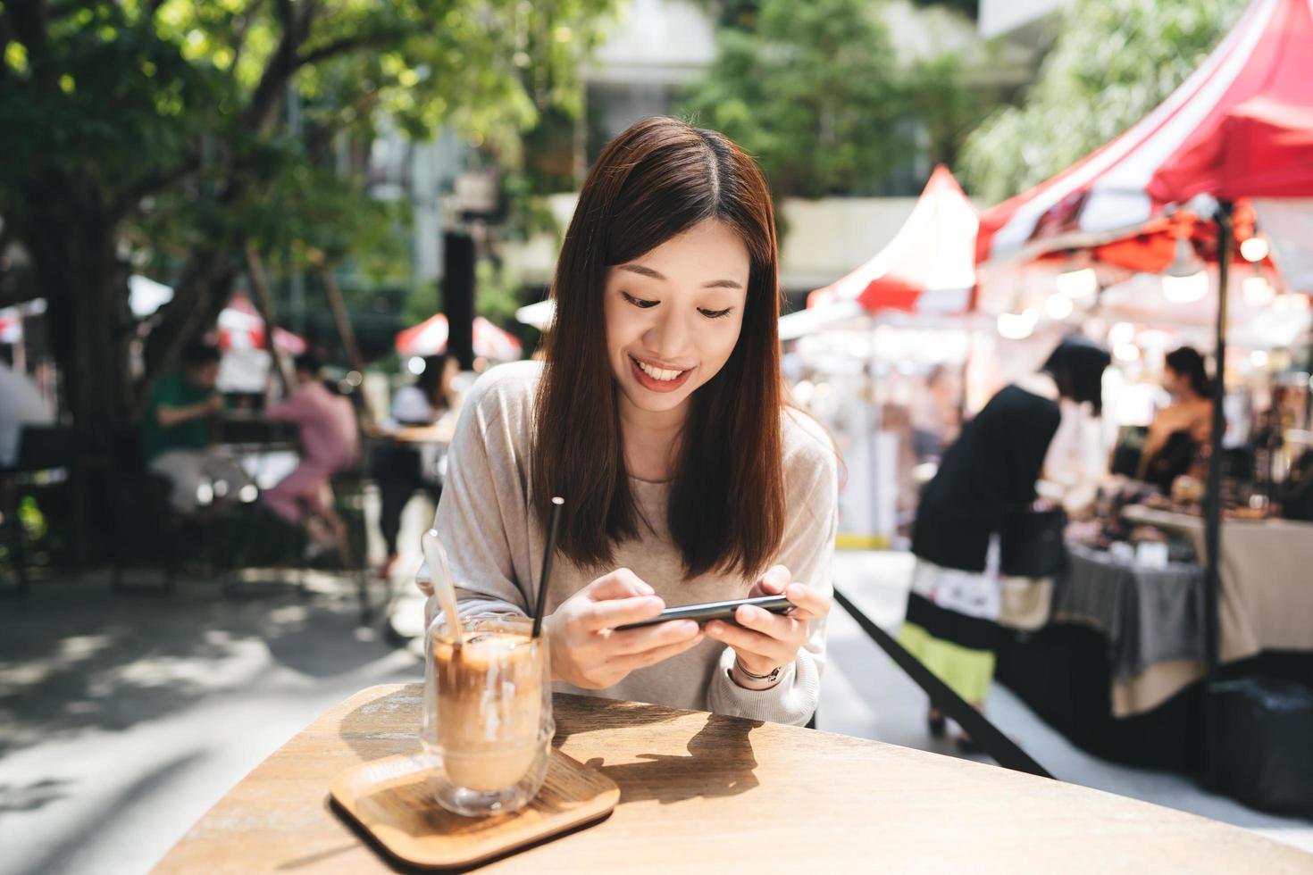 Entspannen Sie asiatische Frau im Café mit Smartphone für soziale Medien. foto