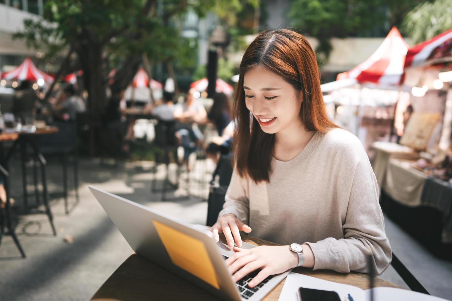 junge erwachsene asiatische frau arbeitet mit laptop-computer im café im freien foto