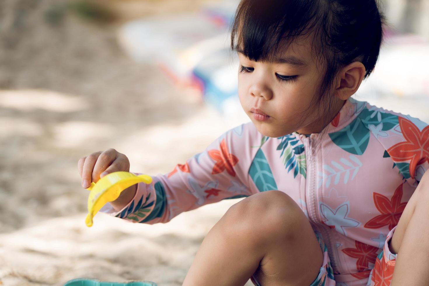 asiatische kindermädchen, die im sand am strand spielen, während sie einen badeanzug tragen. foto