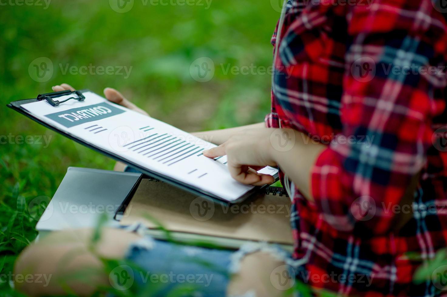 hand des personals, marketingmanager, der auf geschäftsunterlagen zeigt und unter dem baum sitzt - geschäftsideen foto