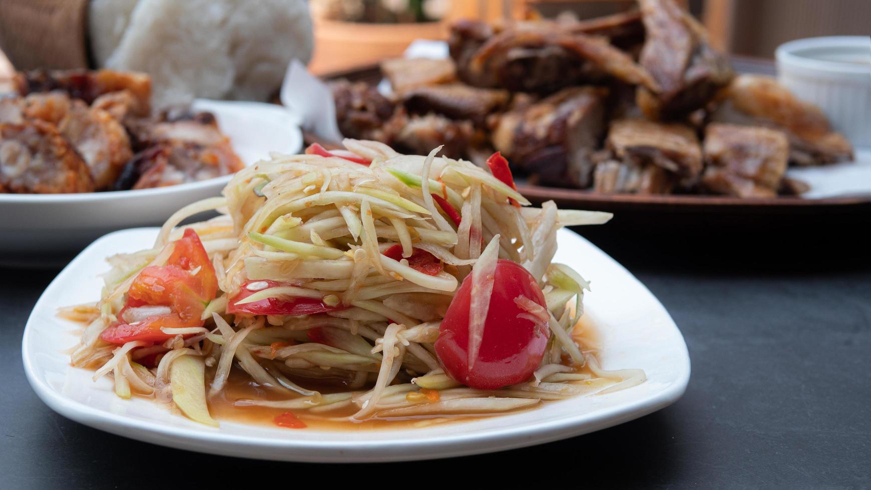 Papaya Salat. hausmannskost in der küche das beliebteste essen in thailand ist scharf, sauer, lecker. Hauptzutaten sind rohe Papaya, Zitrone, Tomate, Knoblauch, Chili foto