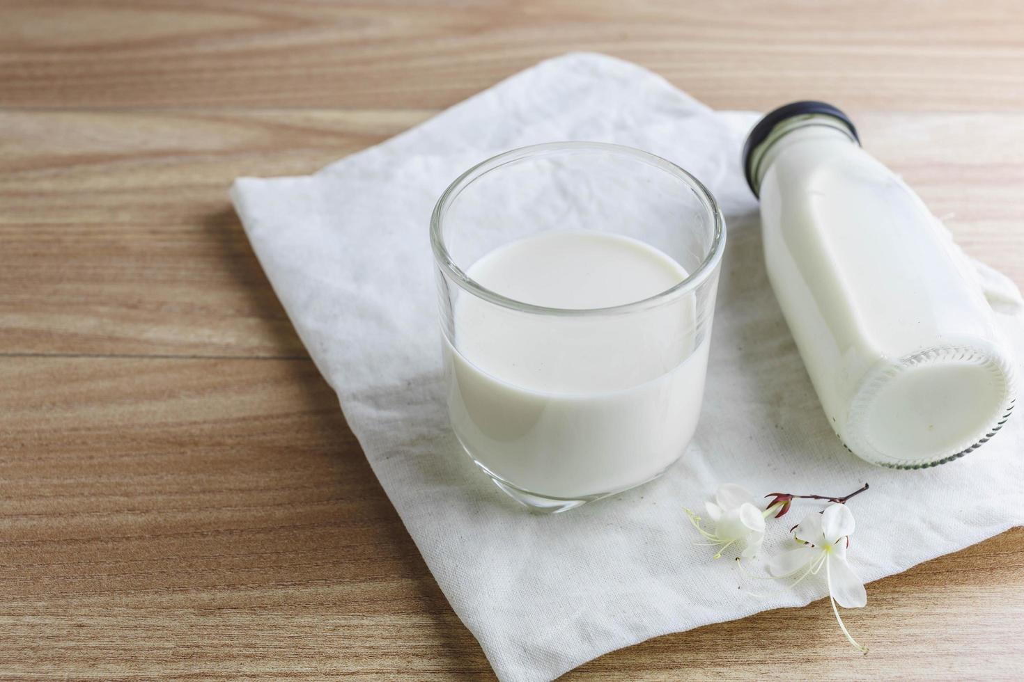 Milchflasche und Glas Milch auf Holztisch foto