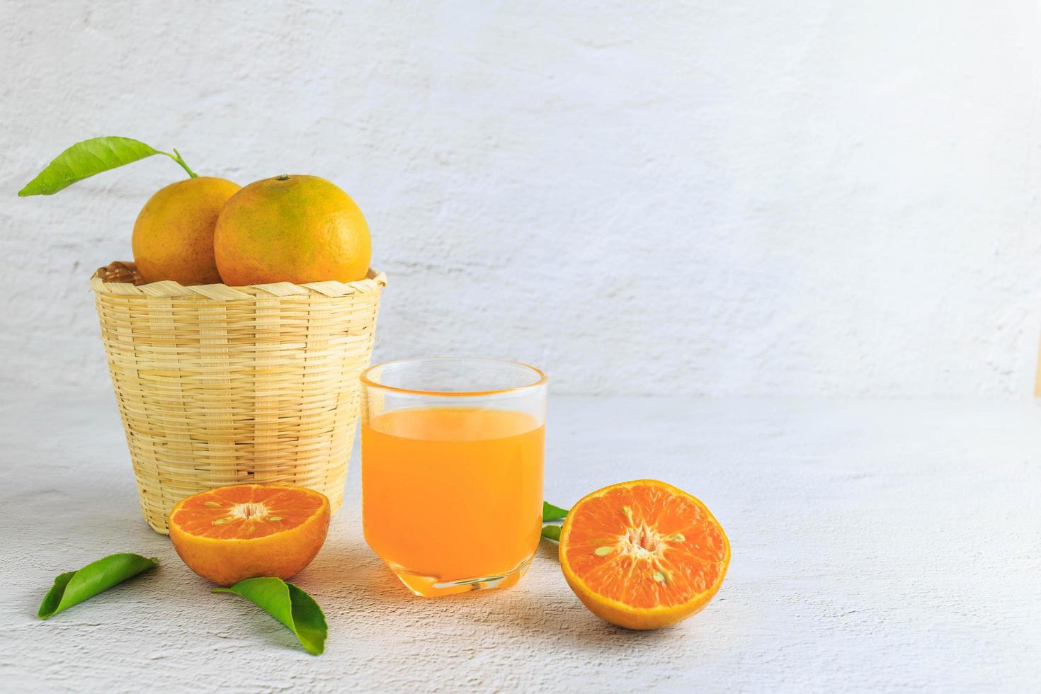 frischer Orangensaft mit Orangenfrucht im Korb foto