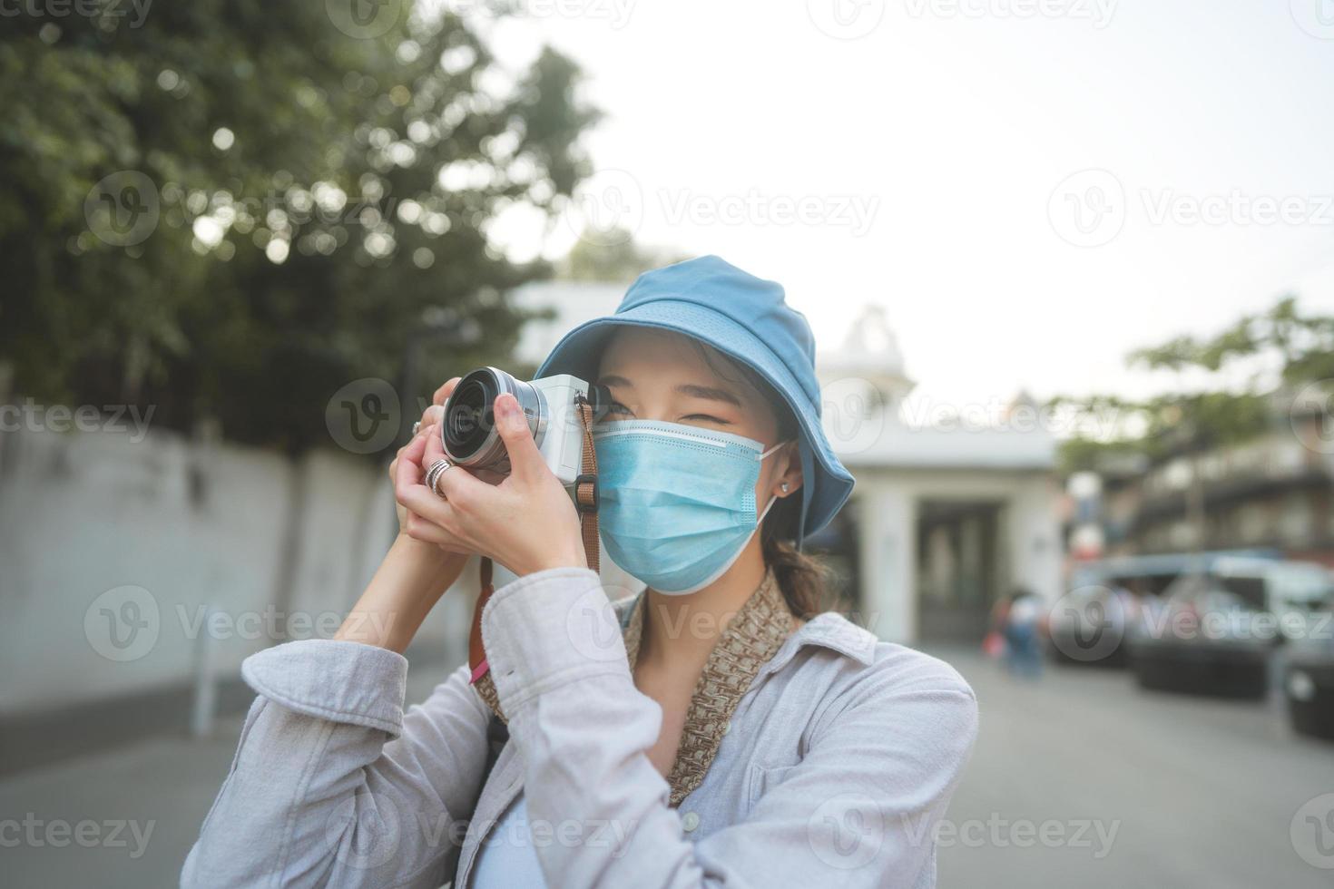 junge erwachsene asiatische frau rucksack reisende tragen gesichtsmaske machen ein foto mit der kamera.