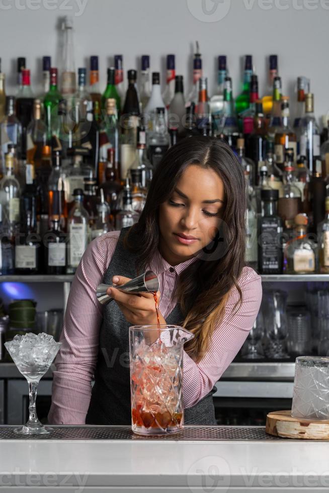 Professionelle Mixologin bereitet Cocktails in der Bar zu foto