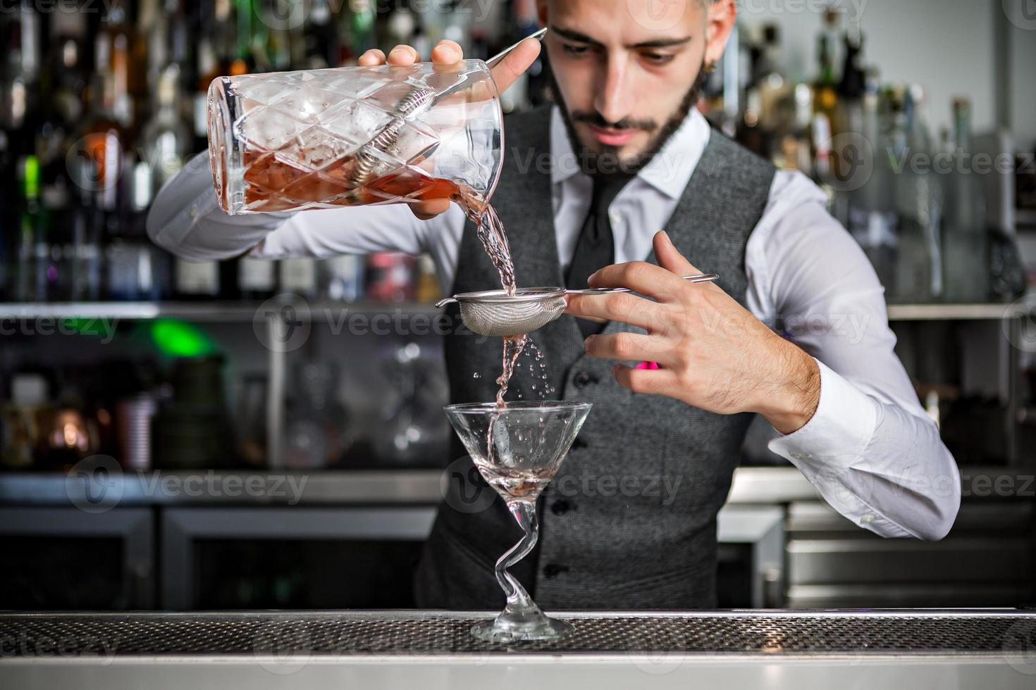 barkeeper gießt cocktail in glas foto