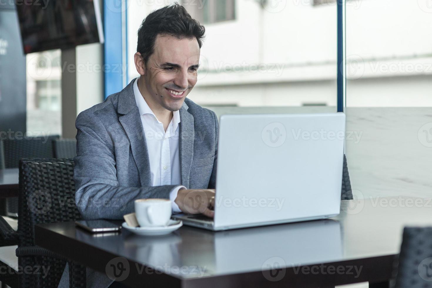 glücklicher geschäftsmann, der mit laptop im modernen café arbeitet foto