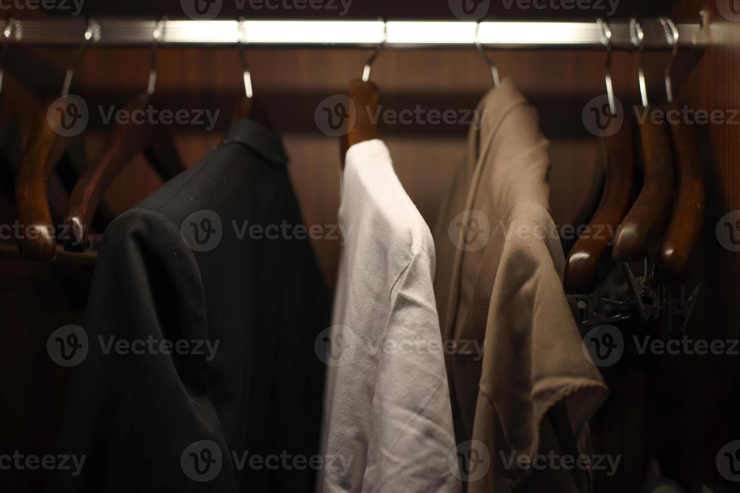 Kleidung auf Kleiderbügeln aufgehängt und im Schrank aufgereiht foto