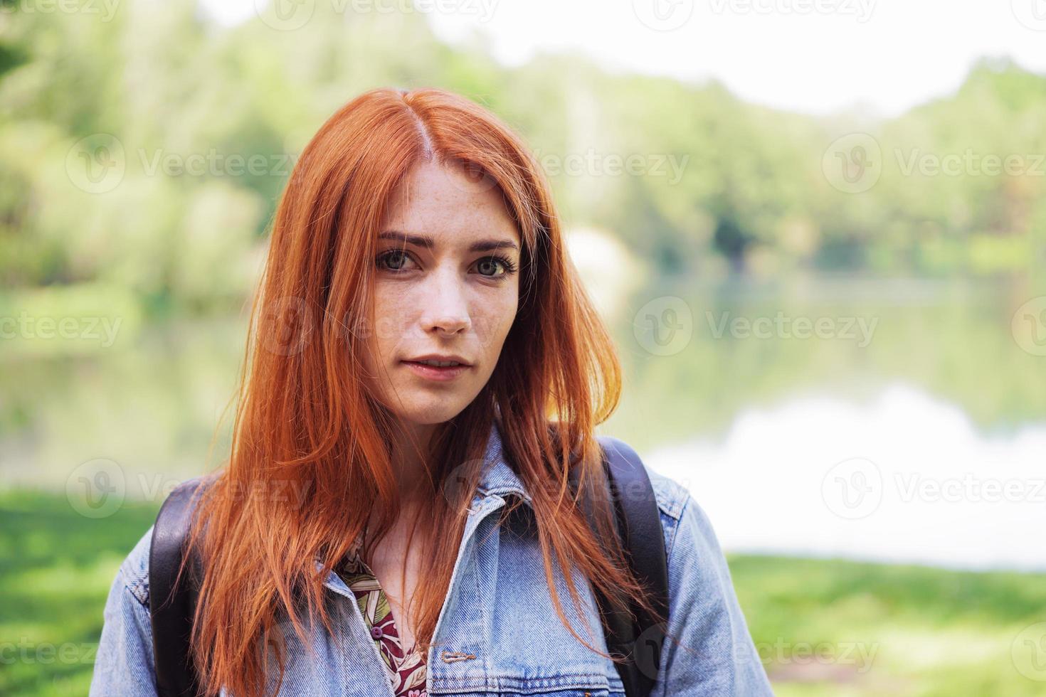 authentische junge Frau mit Jeansjacke und Rucksack im Freien auf einer Wanderung foto