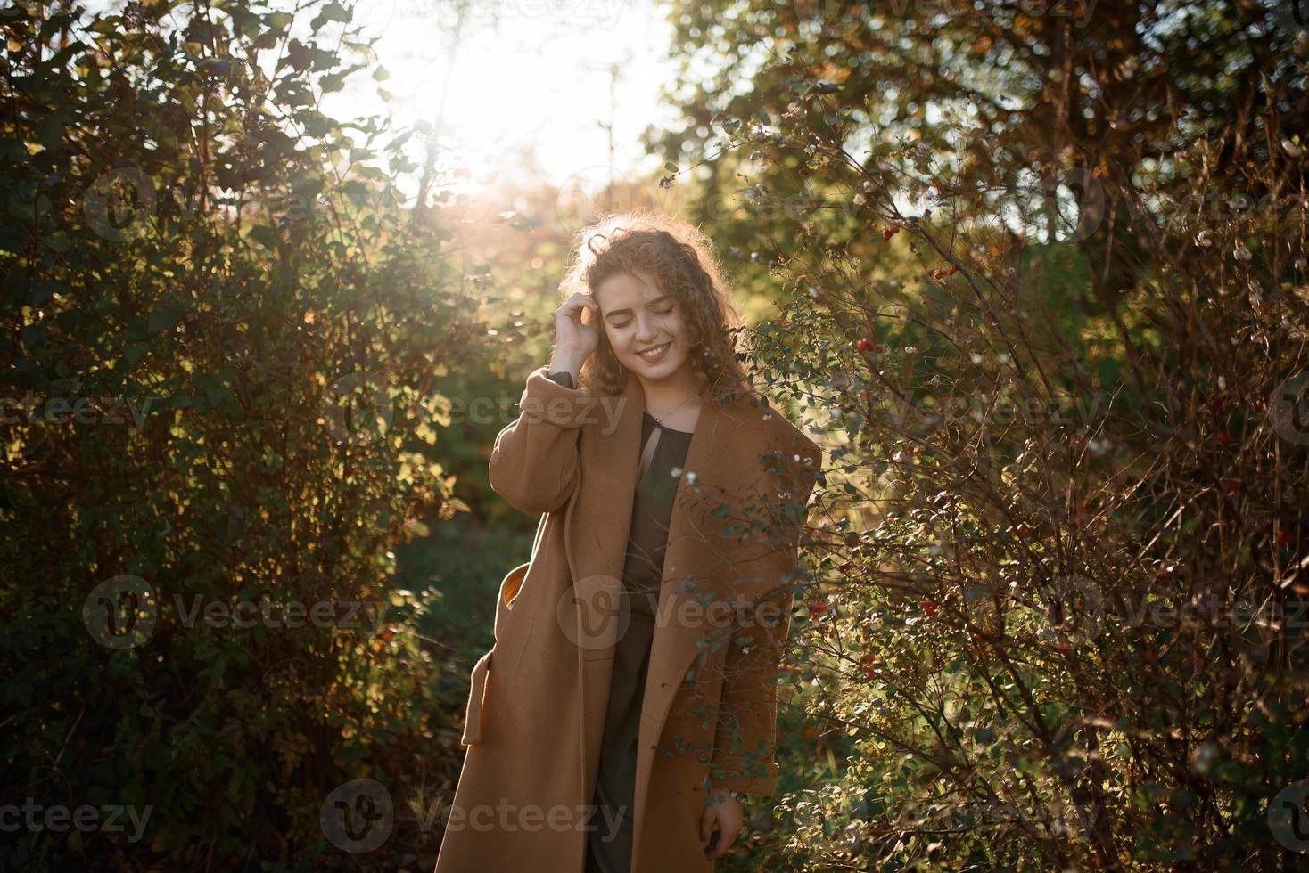 schöne elegante Frau, die im Herbst in einem Park steht foto