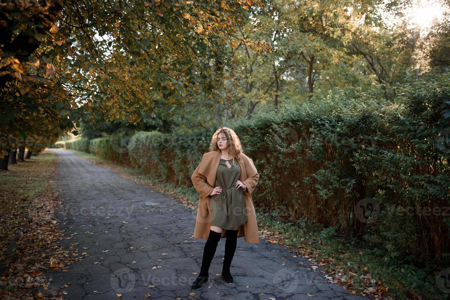 schöne elegante Frau, die im Herbst in einem Park steht foto