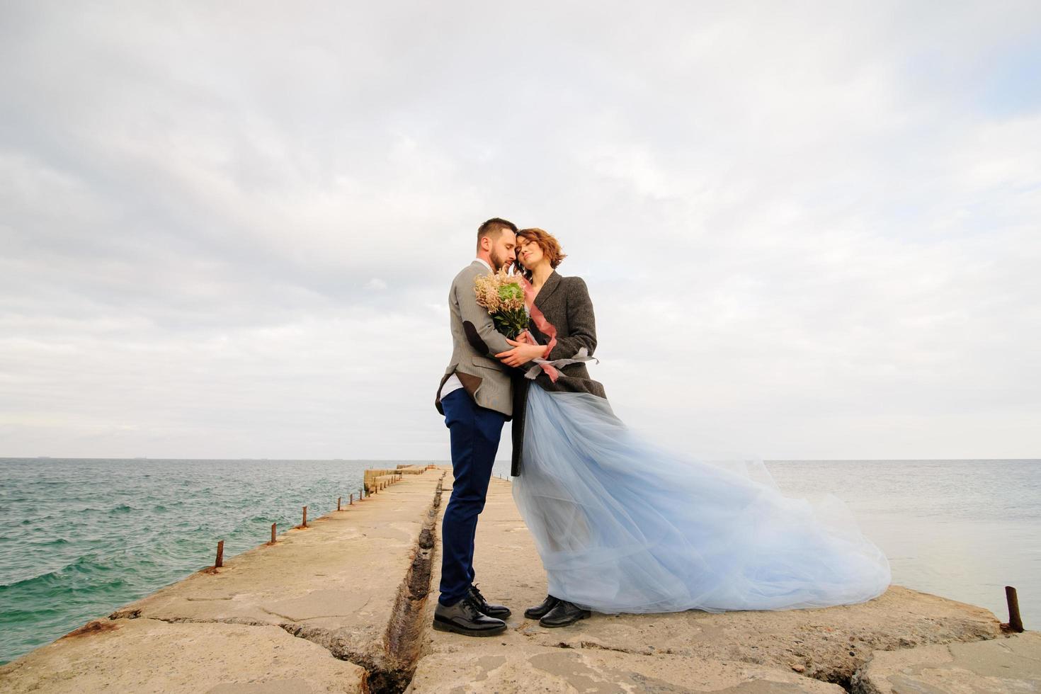 Hochzeitsfotosession eines Paares an der Küste. blaues hochzeitskleid an der braut. foto