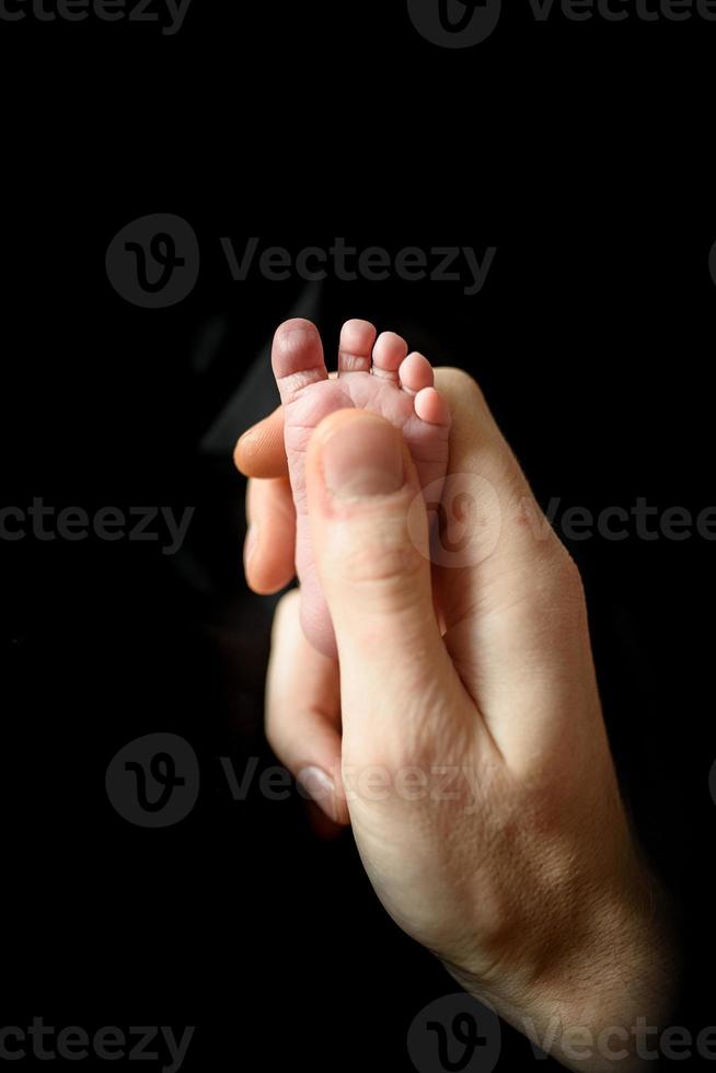 Ein Vater hält den winzigen Fuß seines neugeborenen Sohnes. foto