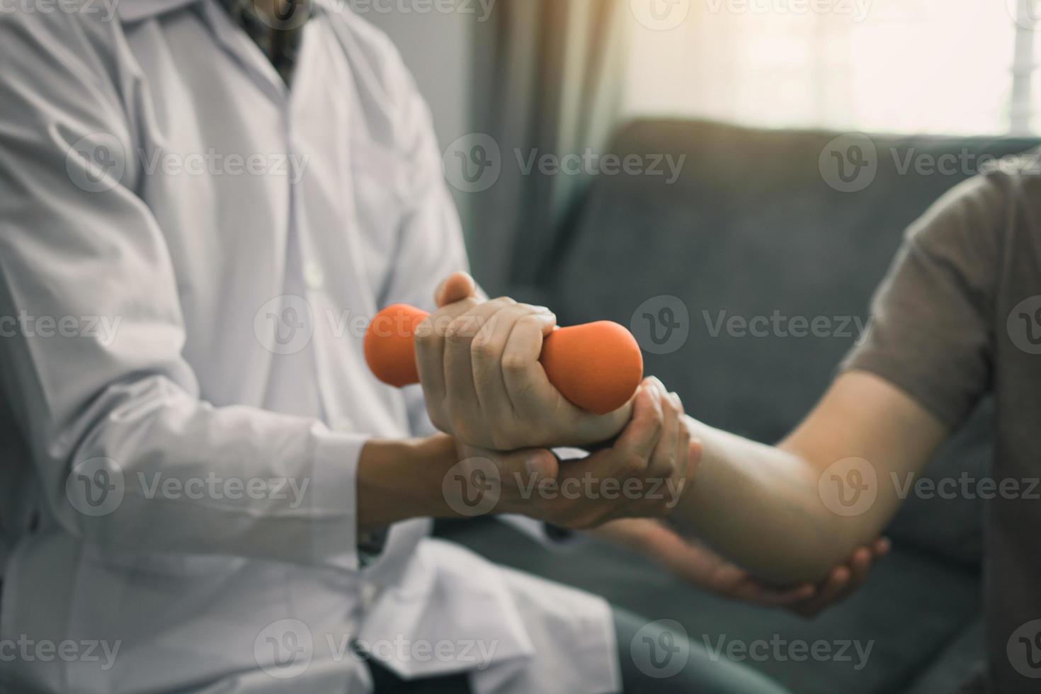 asiatischer junger männlicher physiotherapeut, der patienten beim heben von hanteln hilft, übungen im büro. foto