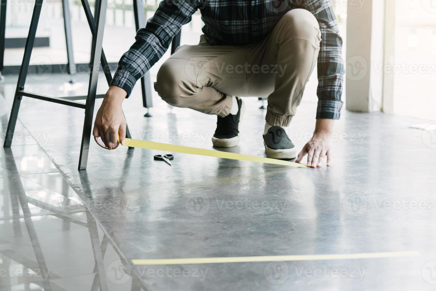 männliche arbeiter, die klebeband vorbereiten, um soziale distanzen zu symbolisieren. foto