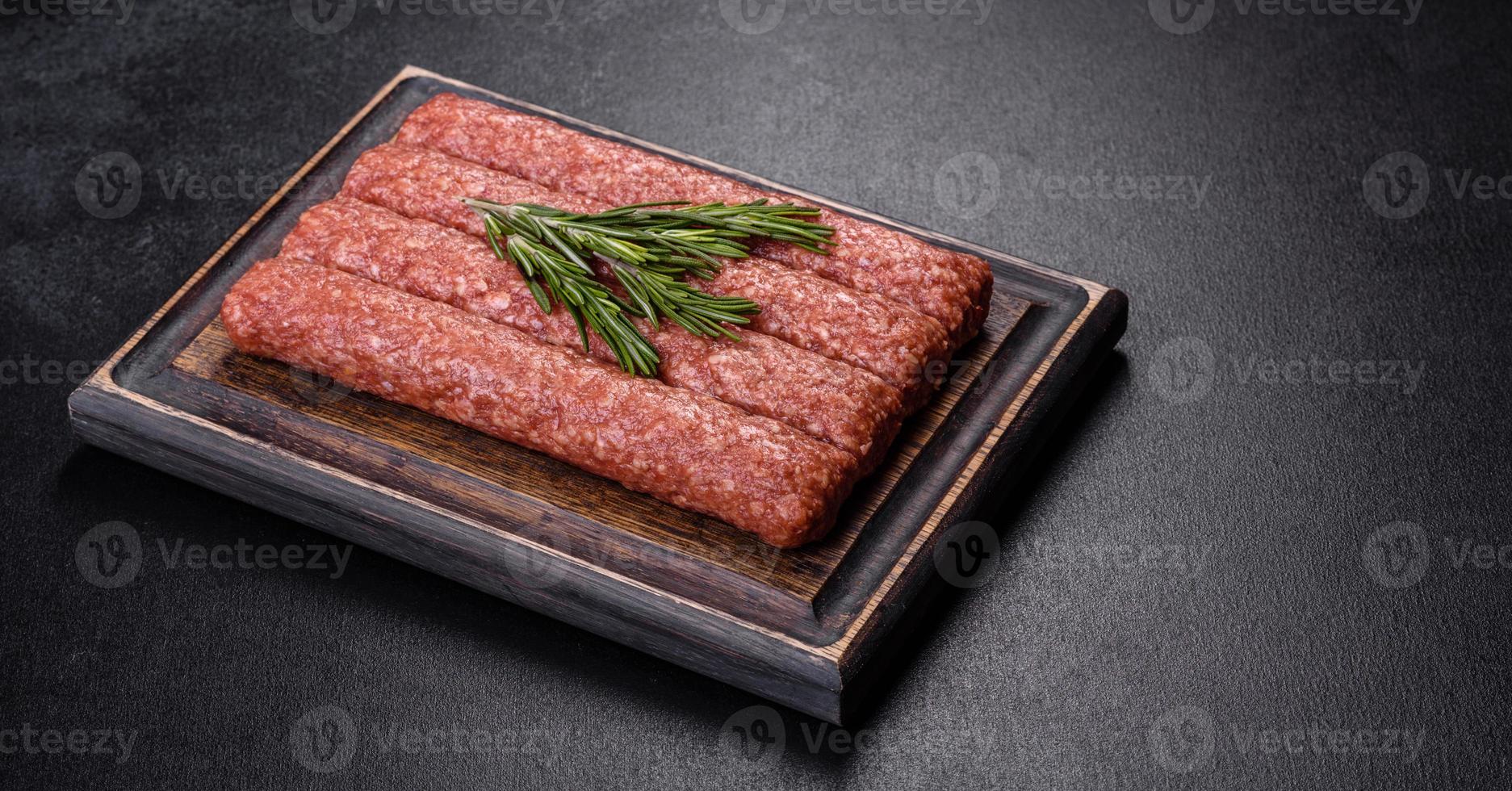frisches rohes hackfleisch für gegrillten kebab mit gewürzen und kräutern auf dunklem betonhintergrund foto