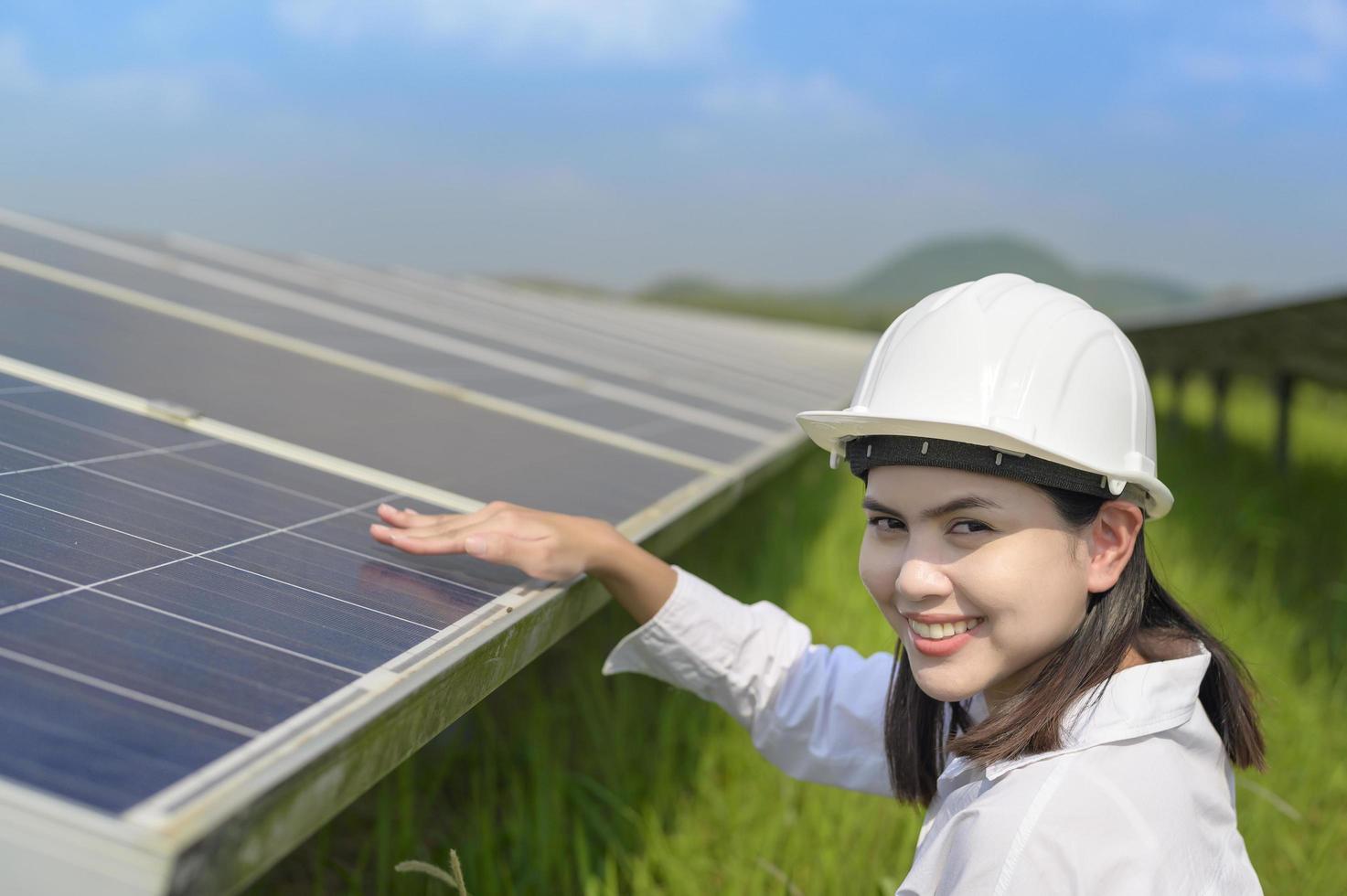 Ingenieurin mit Helm auf dem Feld der Photovoltaikzellen oder Sonnenkollektoren, umweltfreundliche und saubere Energie. foto