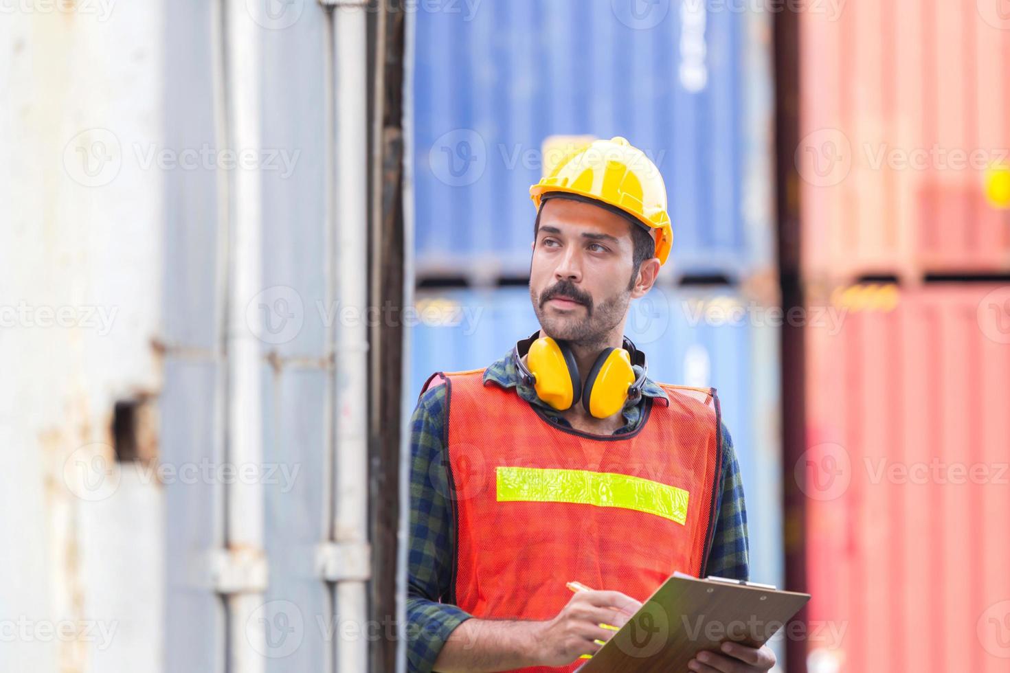 arbeitermann, der zwischenablage-checkliste hält und containerbox von der fracht überprüft foto