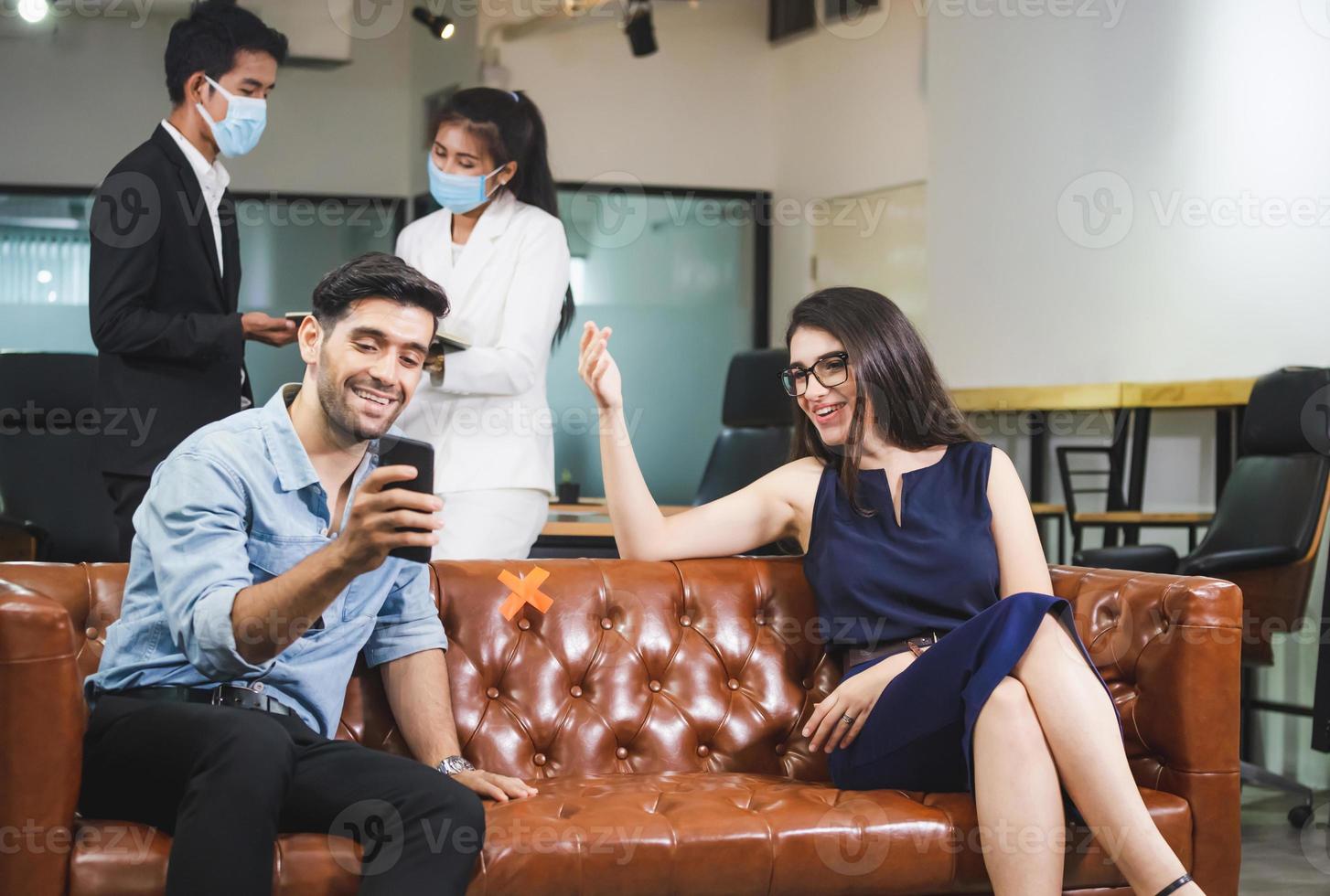 neues normales konzept, mann und frauen sitzen entspannt, mitarbeiter tragen schutzmaske gegen coronavirus im modernen büro foto