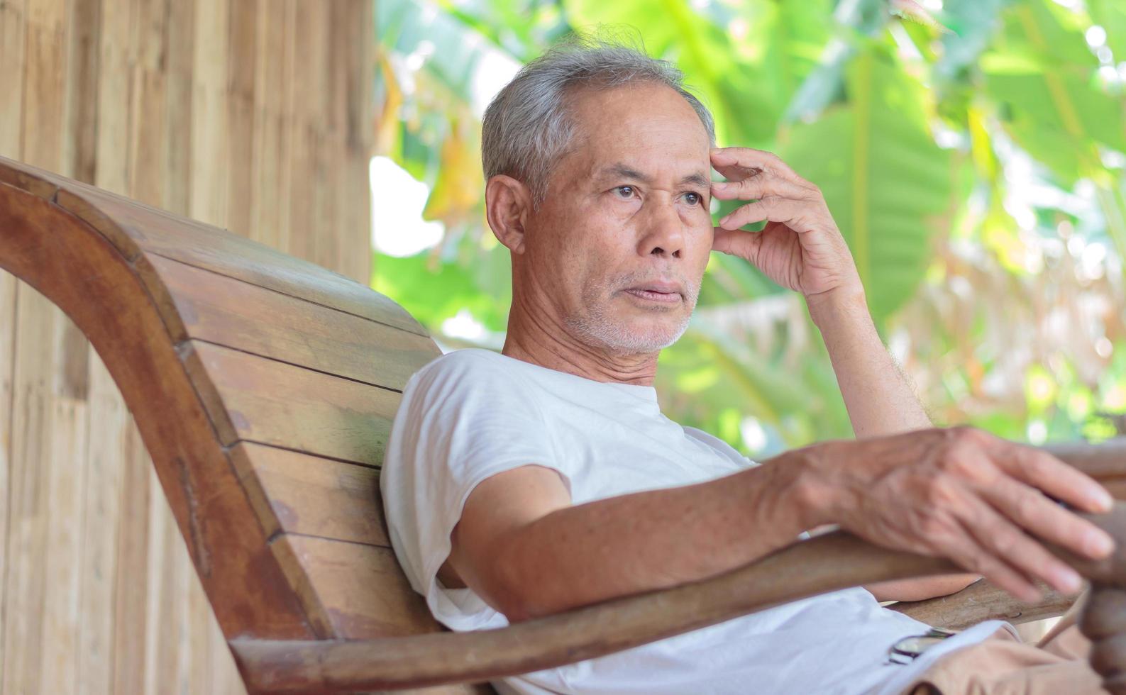 asiatischer älterer mann auf schaukelstuhl, der das leben im ruhestand entspannt foto