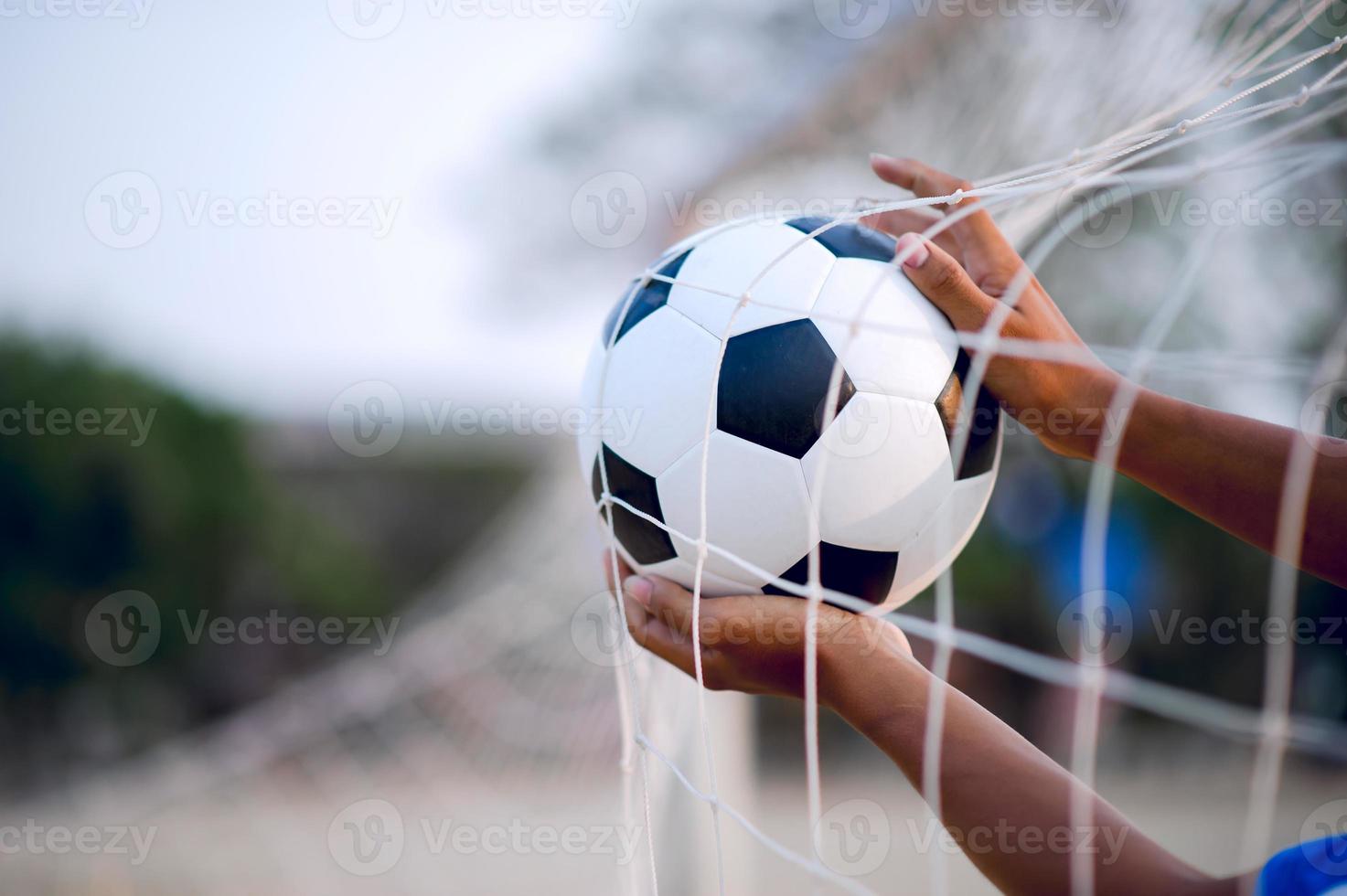 das zugeschnittene Bild von Sportlern, die den Ball und das Fußballfeld fangen. Sport-Image-Konzept. foto