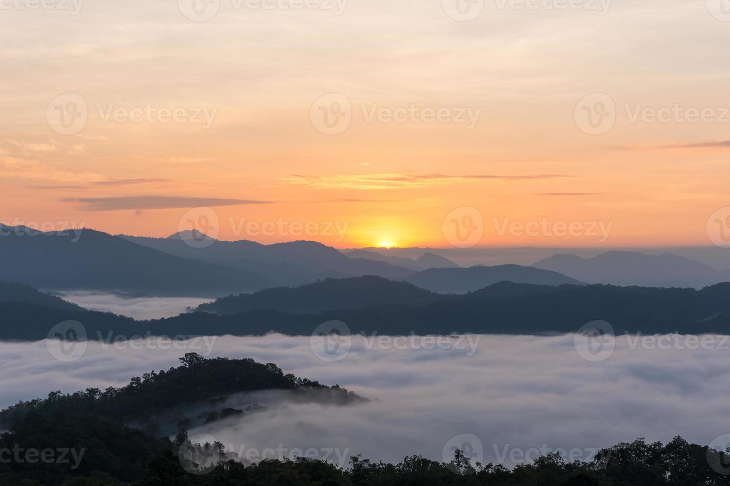 Sonnenaufgang über großen Bergen und der Nebel über dem Wald im Winter foto