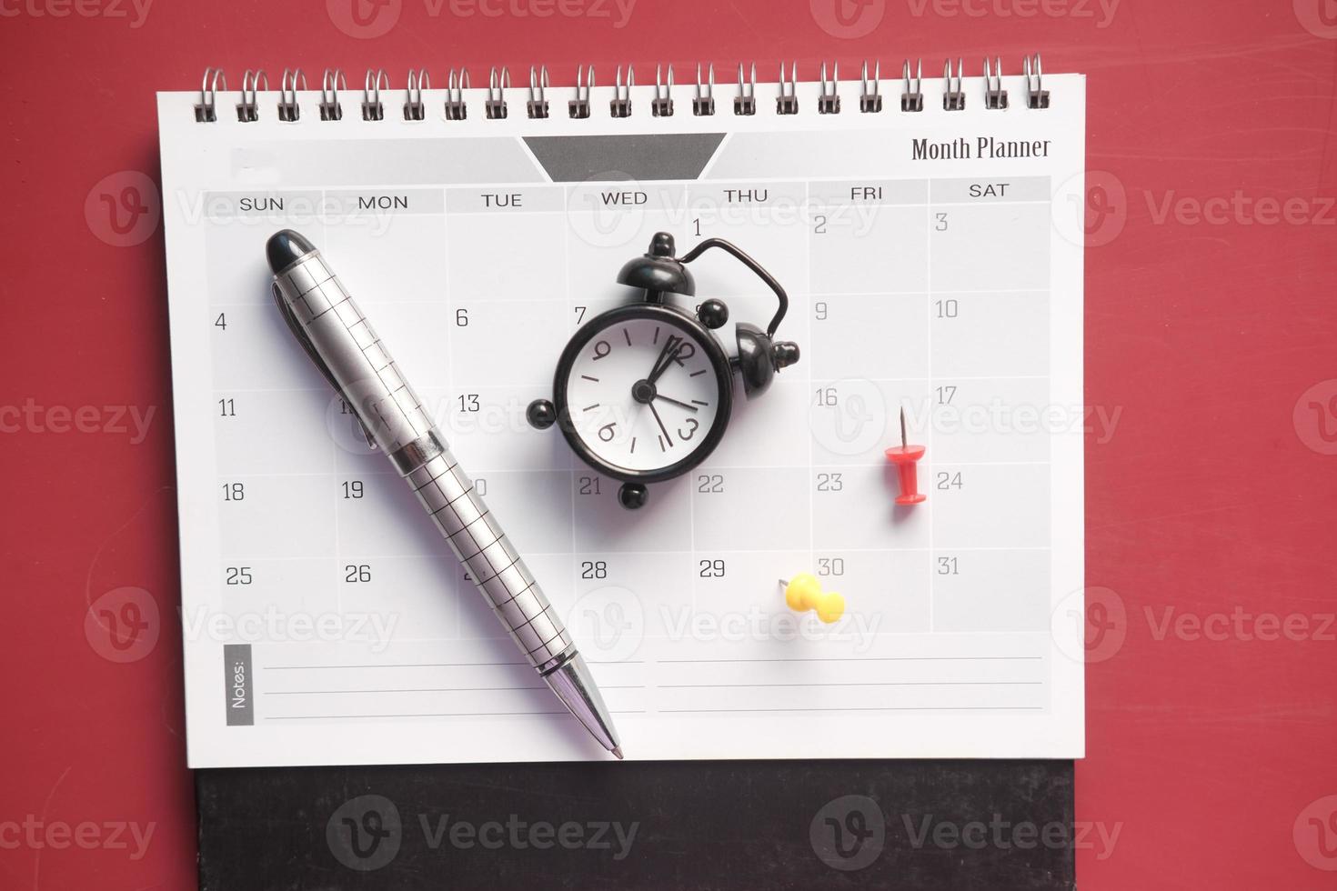 alter Wecker und Kalender auf rotem Hintergrund. foto