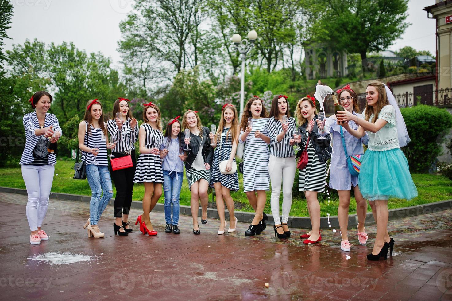 elf attraktive Zopfmädchen mit hübscher Braut feiern Junggesellinnenabschied mit Champagner im Park. foto