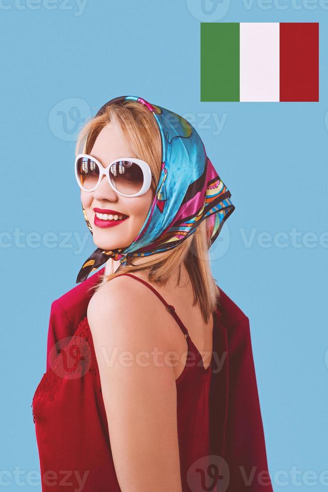 stilvolle lächelnde, fröhliche, schicke blonde Frau mit Make-up in Halstuch und Sonnenbrille auf blauem Hintergrund foto