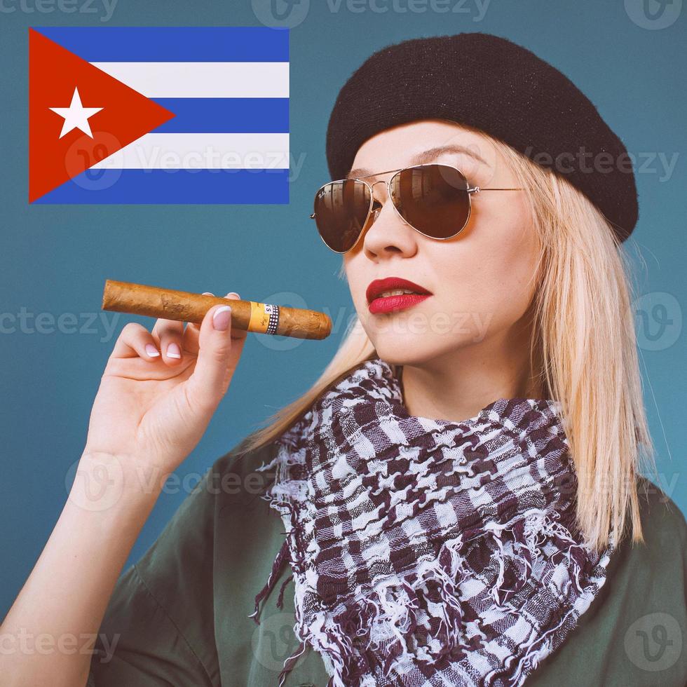 Porträt einer blonden schönen Frau mit Hut und Sonnenbrille mit Zigarre im kubanischen Che Guevara-Stil foto