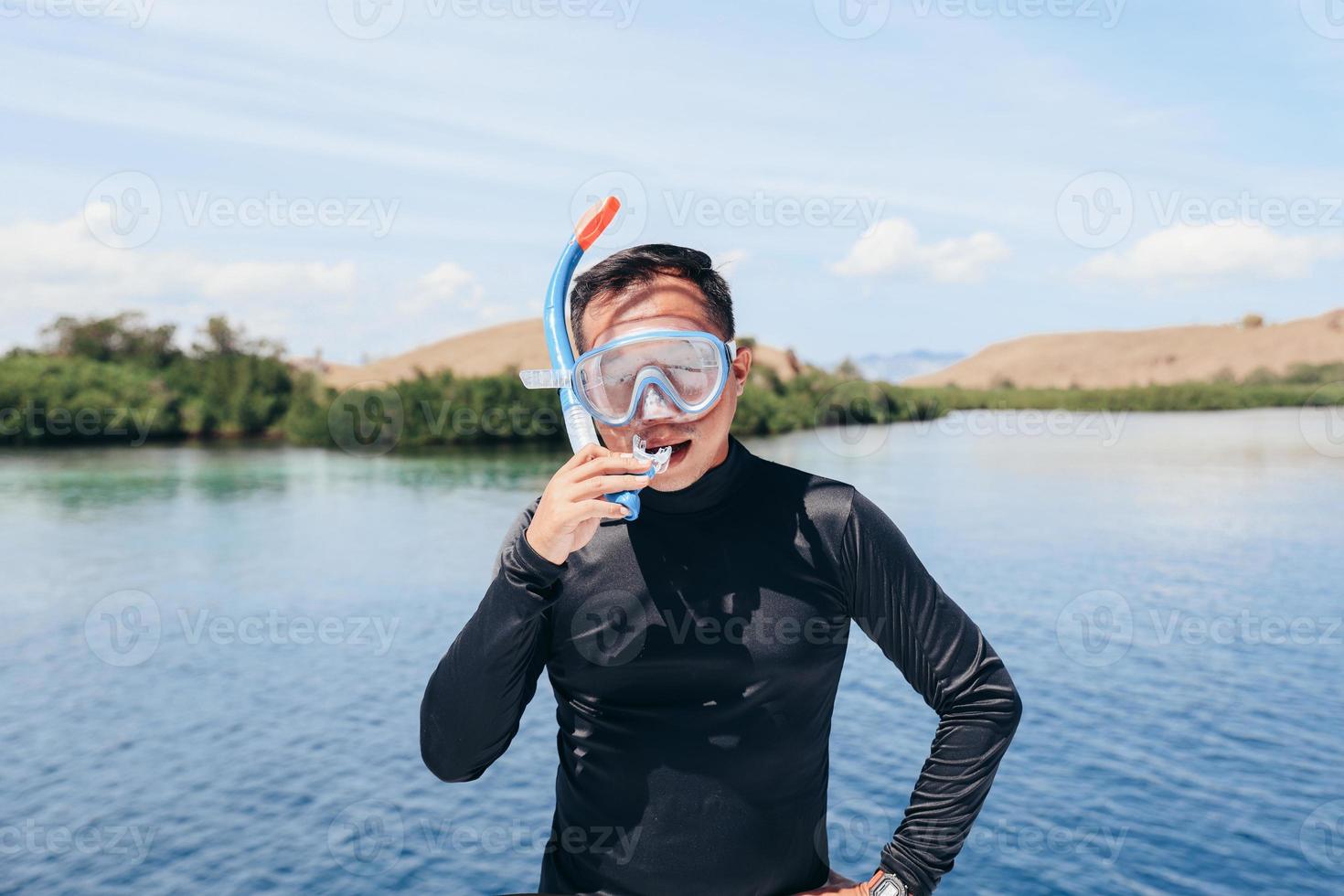asiatischer mann in schnorchelmaske mit neoprenanzug, der sich auf das schnorcheln im sommerurlaub vorbereitet foto