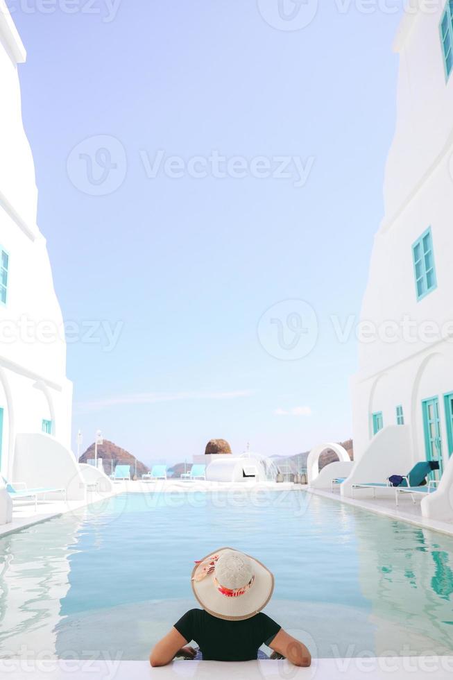 Touristin im Sommerhut, die sich am Sommertag am Pool entspannt foto