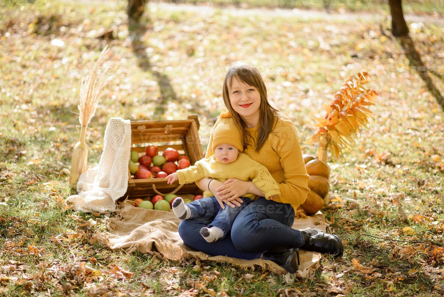 junge mutter, die baby gefallene blätter zeigt foto