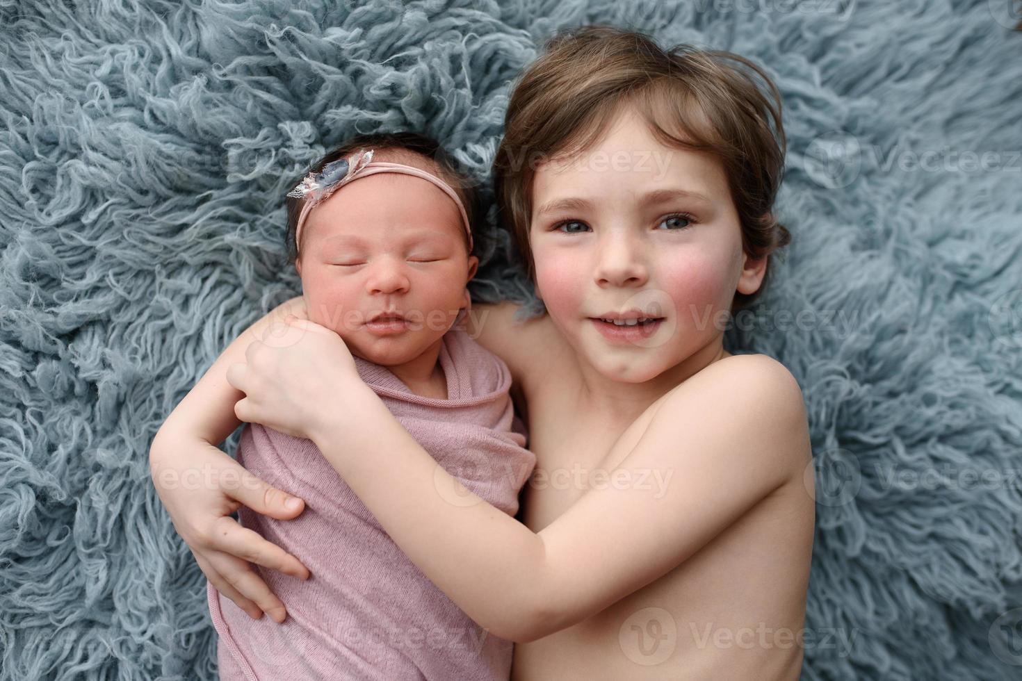 älterer bruder umarmt seine neugeborene schwester. Schuss aus dem oberen Winkel. foto