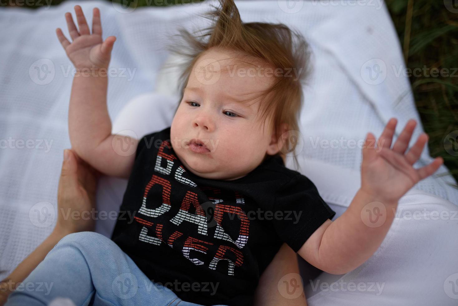 Bild eines entzückenden kleinen Mädchens, das auf Gras sitzt und ein lustiges Gesicht macht, geringe Schärfentiefe foto