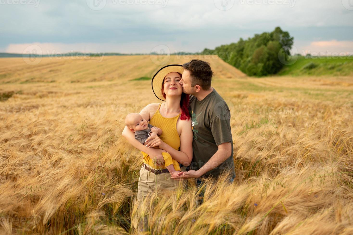 vater, mutter und ihr kleiner sohn haben gemeinsam spaß auf einem weizenfeld. foto