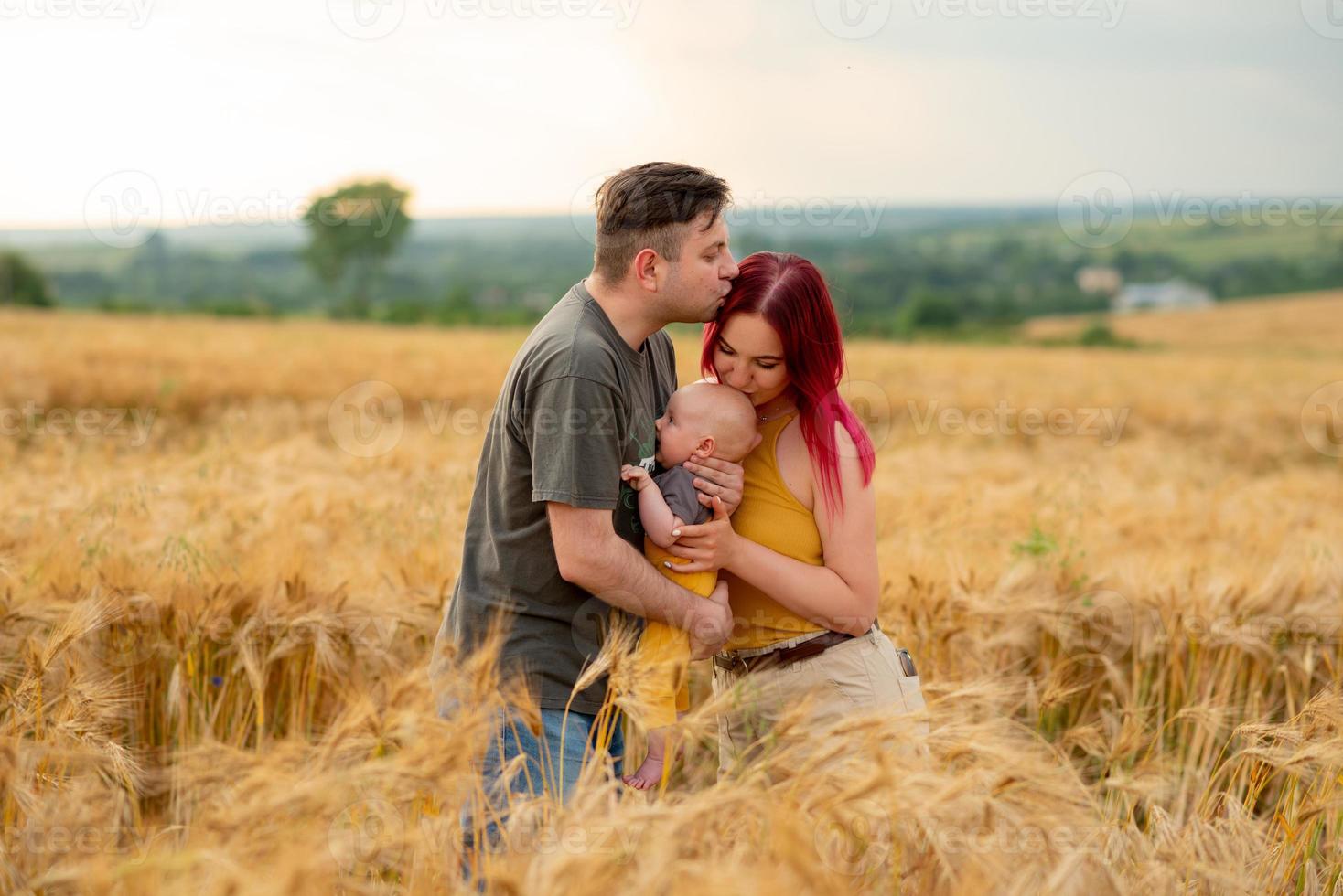 vater, mutter und ihr kleiner sohn haben gemeinsam spaß auf einem weizenfeld. foto