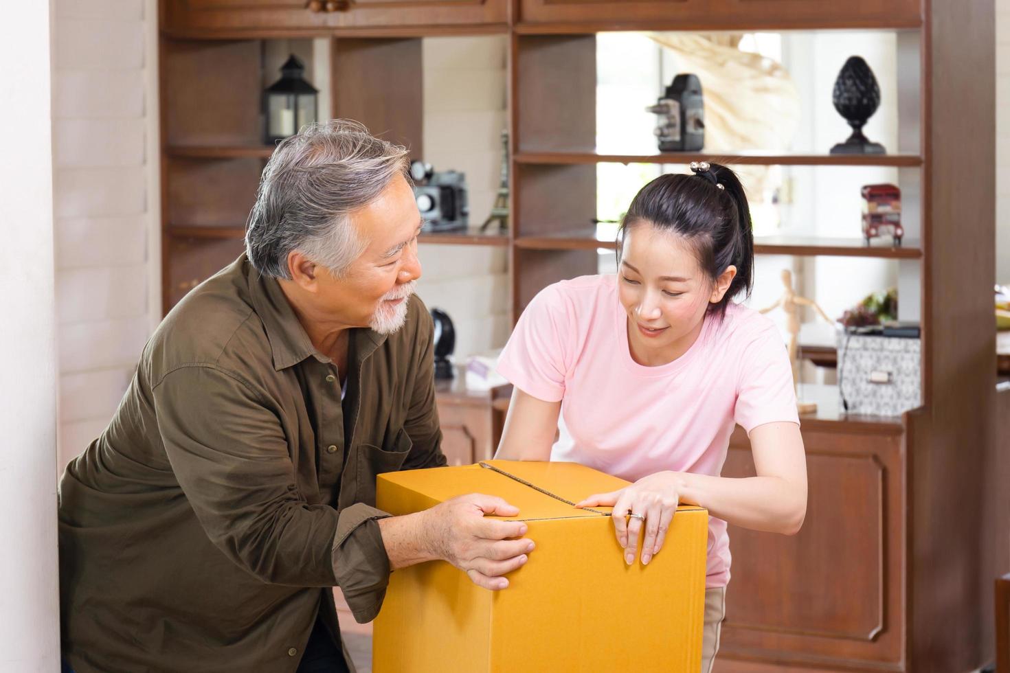 Umzugstagskonzepte, asiatische Familie, die Kisten in ein neues Zuhause trägt, glückliche Tochter im mittleren Alter und älterer Vater im neuen Haus foto
