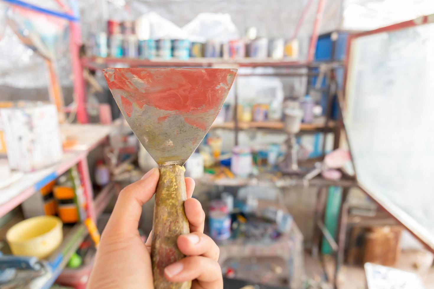 Handwerker Maler Handhalter mit Spachtel über verschwommenem Hintergrund, Autoreparaturkonzept foto