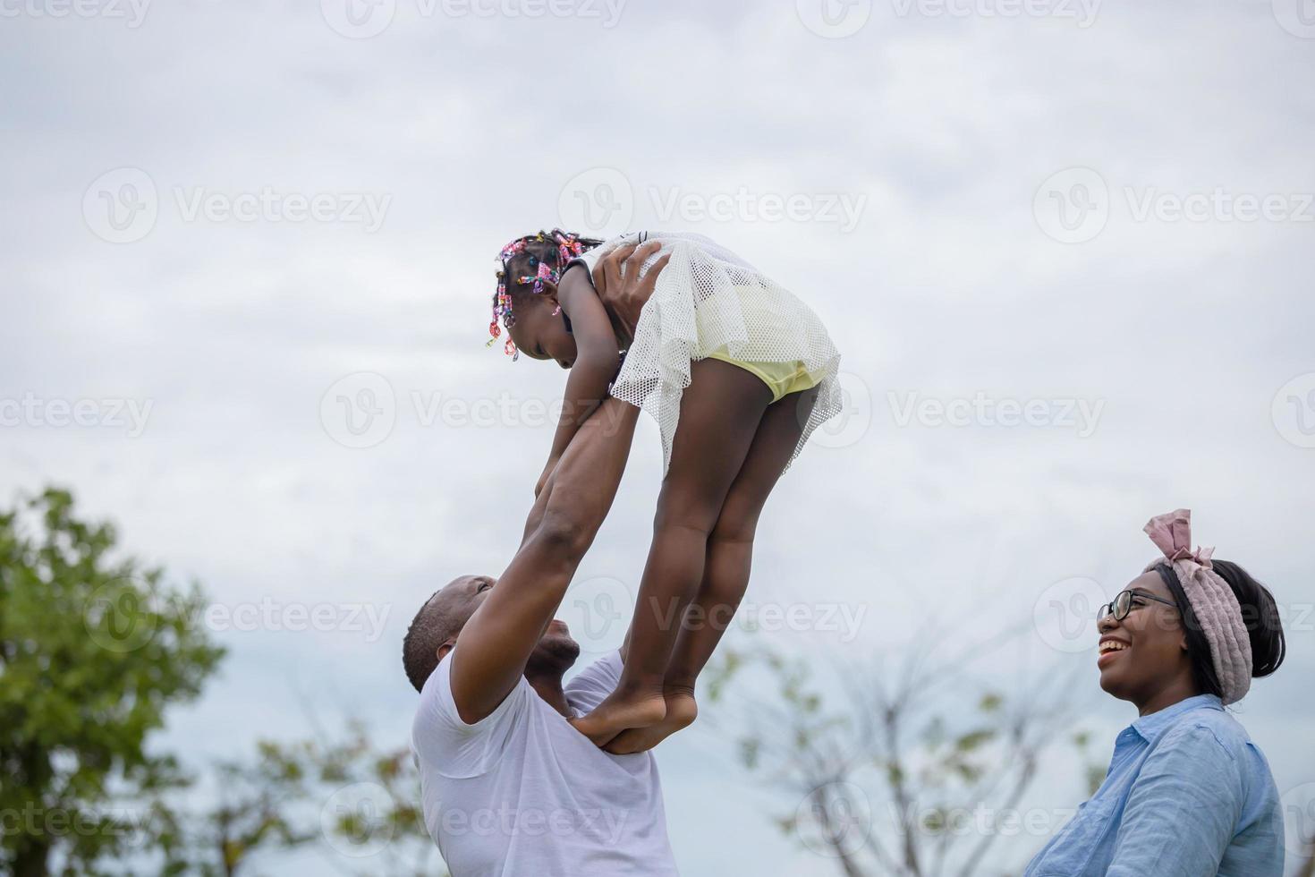 glücklicher vater, mutter und tochter, die zusammen im freien spielen, fröhliche afroamerikanische familie, die im park genießt, glücksfamilienkonzepte foto