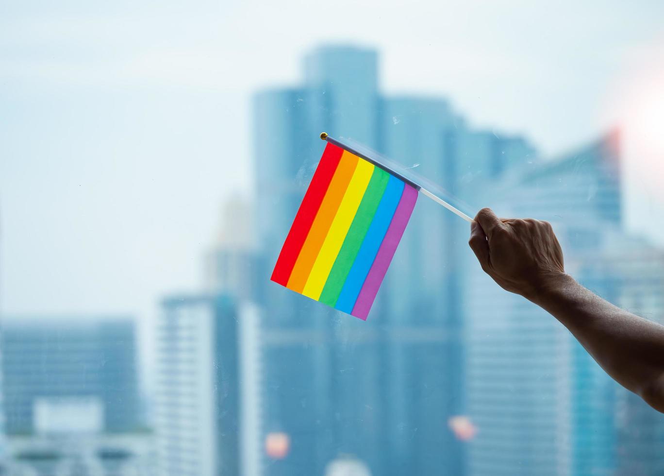 Bürogebäudehintergrund mit einer Regenbogen-Gay-Pride-Flagge auf der Hand des älteren Mannes in der Geschäftsstelle foto