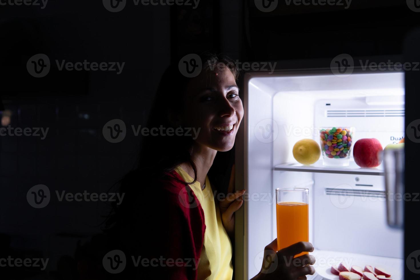 eine schwangere Frau, die spät in der Nacht aufwacht und im Kühlschrank nach Essen sucht foto