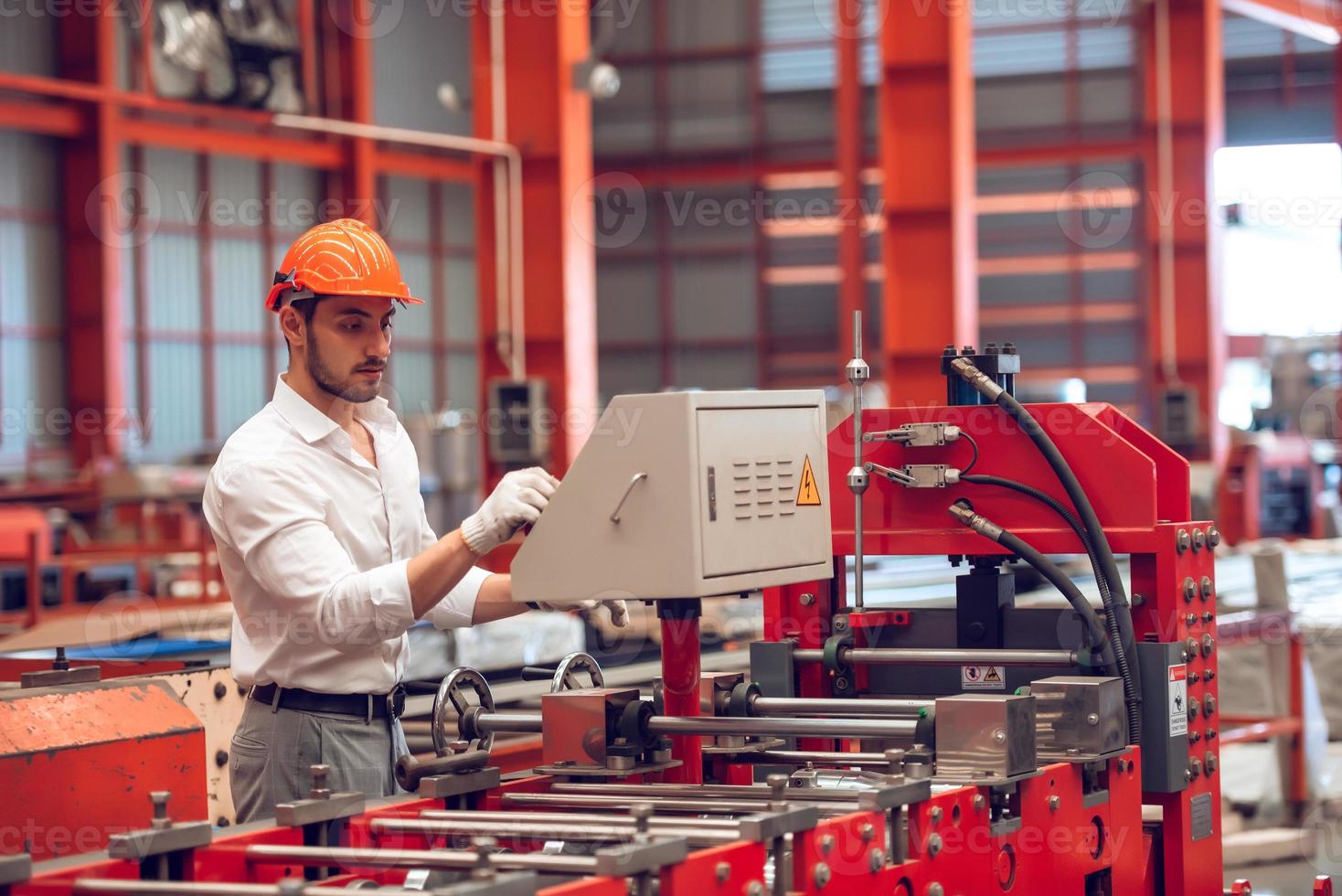 fabrikarbeiter, der den prozess der elektrischen maschine auf der industriearbeitsstelle überprüft und aus sicherheitsgründen einen harten hut trägt foto