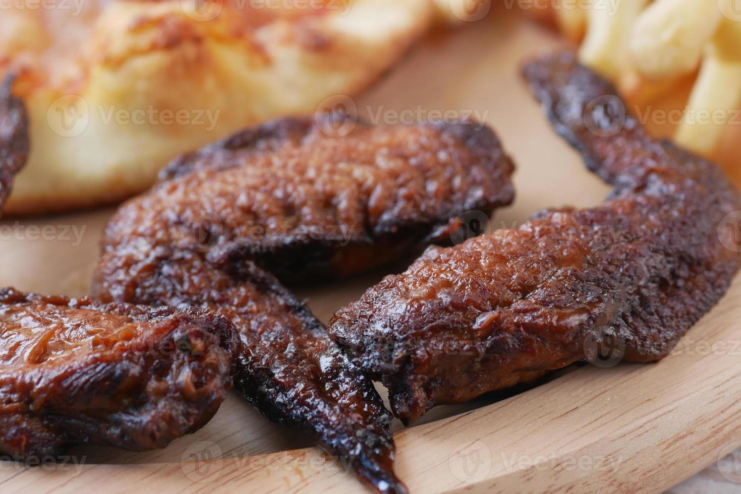 Chicken Wings und Pizza auf Holzplatte auf dem Tisch foto