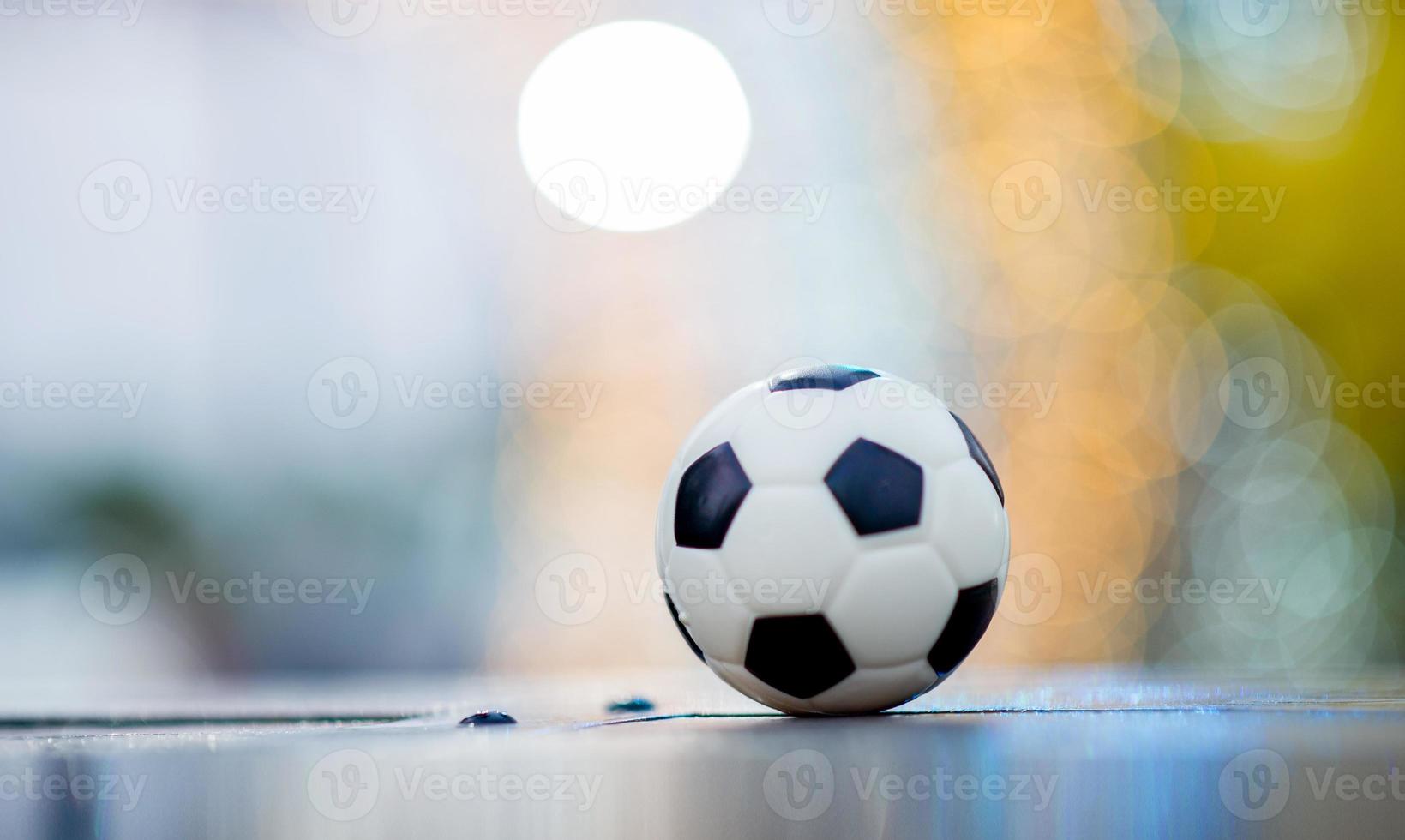 Der Fußball ist auf einem Holzboden platziert und hat einen unscharfen Hintergrund mit schönem Bokeh. foto