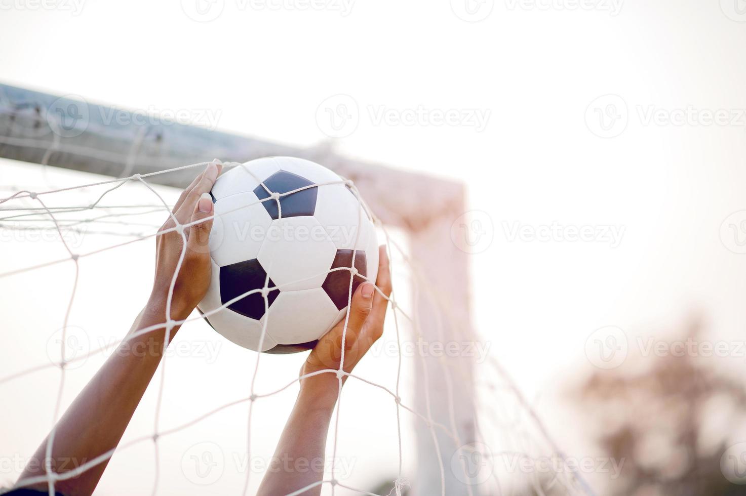 das zugeschnittene Bild von Sportlern, die den Ball und das Fußballfeld fangen. Sport-Image-Konzept. foto